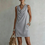 Grey sleeveless mini dress with a relaxed fit, hand tucked into the side pocket detail