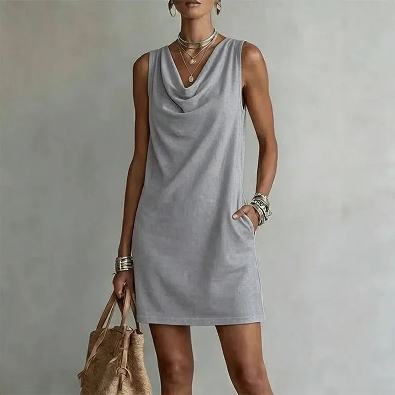 Grey sleeveless mini dress with a relaxed fit, hand tucked into the side pocket detail