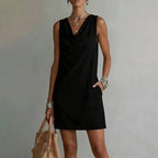 Black sleeveless mini dress shown from the front, highlighting the draped neckline and shift cut