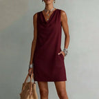 Close-up of the cowl neckline drape on a sleeveless mini dress, paired with layered silver jewellery