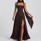 Front view of a brown satin maxi dress with a long draped scarf detail trailing from the halter neckline
