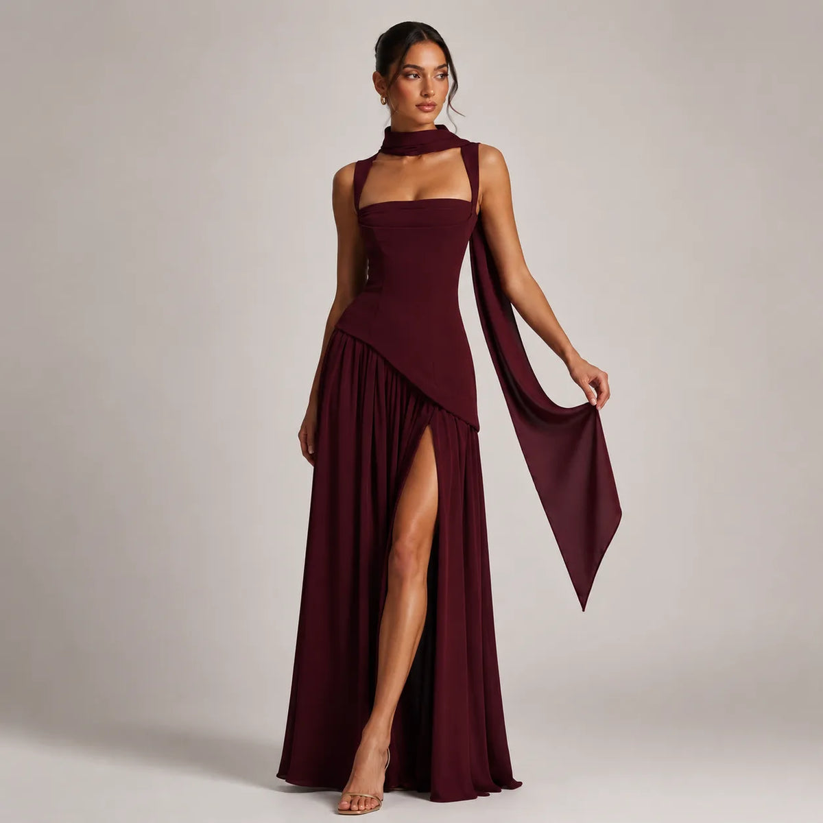 Side view of the burgundy maxi dress with model holding the long trailing scarf to show the fabric drape