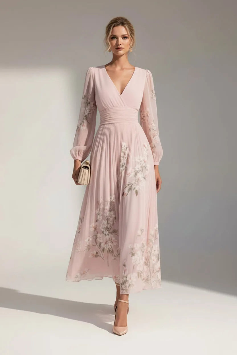 Model wears a blush pink floral chiffon midi dress with long sheer sleeves and a draped V-neckline, standing in natural light