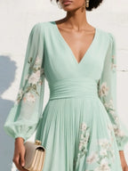 Close-up of the V-neckline and ruched waistband in sage green chiffon with delicate floral sleeve print detail