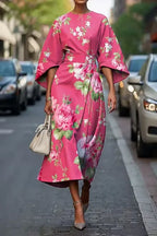 Bold pink floral kimono-sleeve midi dress with large rose print, cinched waist and flowing A-line skirt