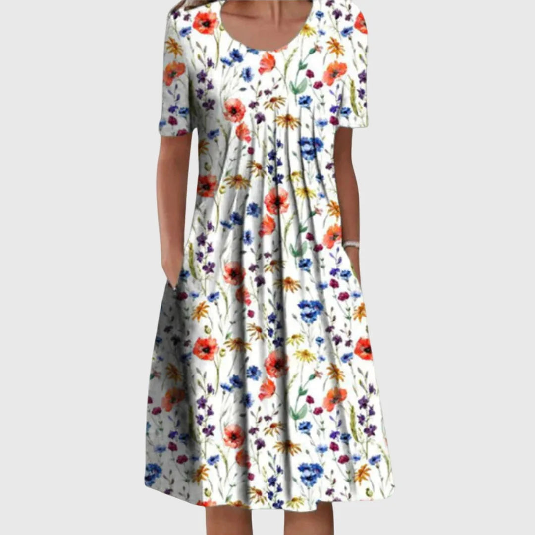 Front view of a floral midi dress in a white base with red poppies, yellow blooms and blue flowers, short sleeves and side pockets