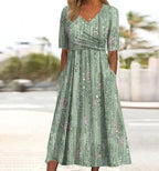 Close-up front view of the green floral midi dress showing the short sleeves, ruched bodice and A-line skirt with side pockets.