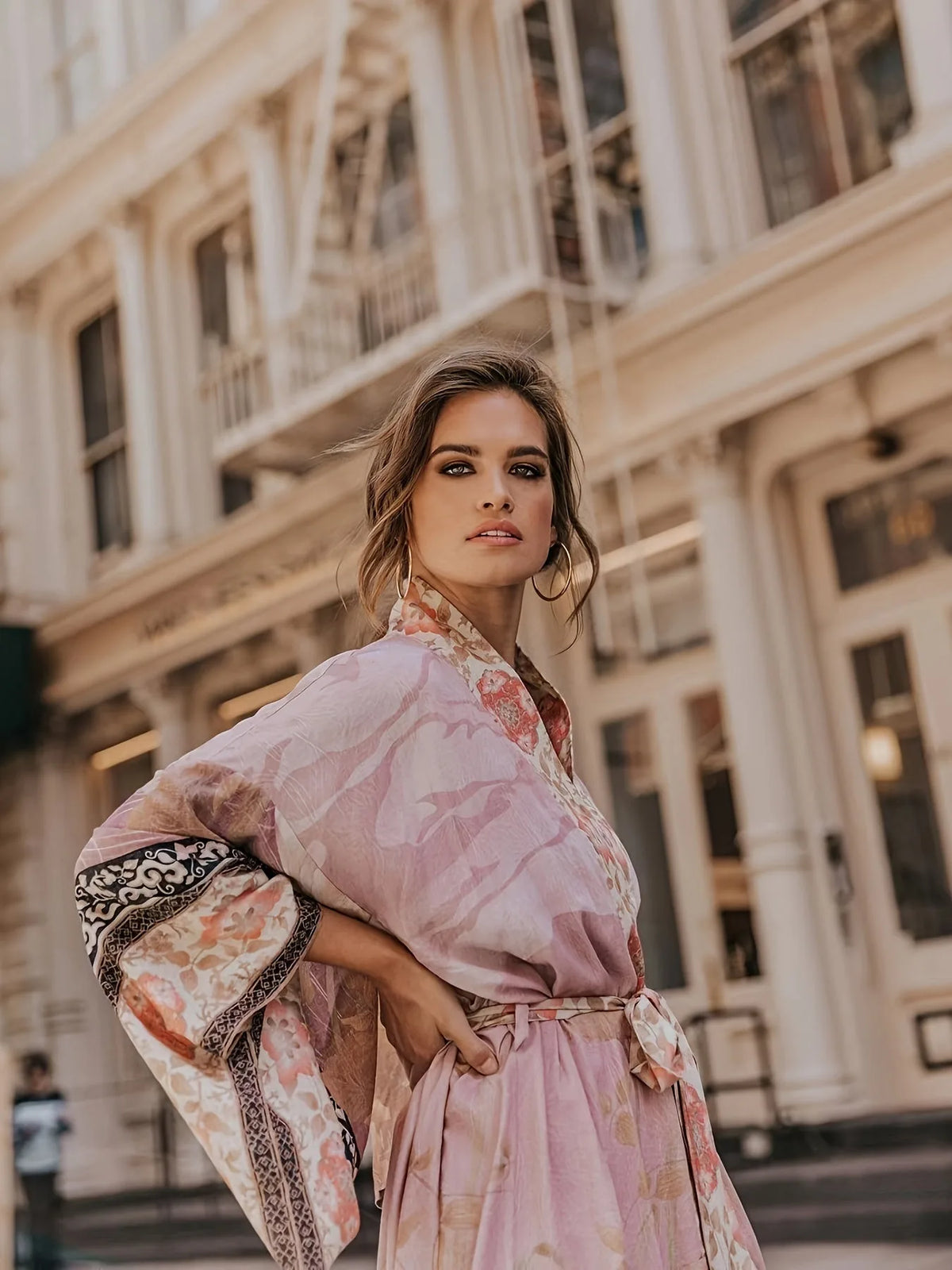 Detail of the dusty rose kimono's draped fabric and sash tie against a plain studio background
