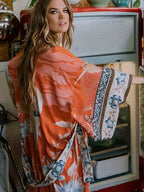 Rear view of rust orange kimono showing wide sleeves with contrast border print in a vintage kitchen setting