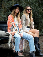 Two friends seated outdoors, one wearing the rust orange floral kimono over jeans and a white tee