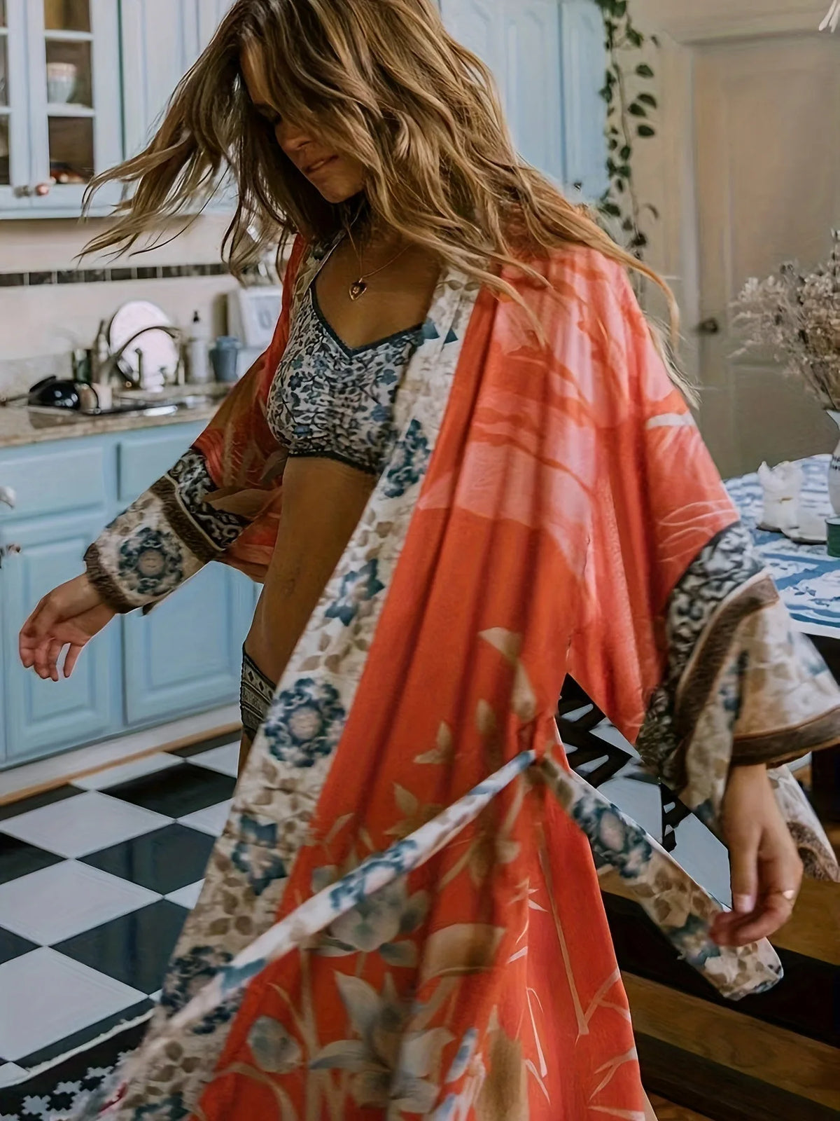 Close-up side view of rust orange kimono swirling in motion, showing the floral and border print detail