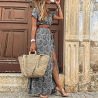 Close-up side view of a grey and white paisley print maxi dress with a brown belt against a weathered doorway