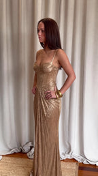 Full length view of gold metallic maxi dress with front leg split and sweeping pleated train on patterned tiles