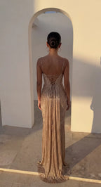 Back view showing lace-up corset detailing and open back of the gold pleated maxi dress in sunlight