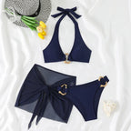 Flat lay of navy bikini top, sheer mesh sarong and bottoms laid out fully untied to show the complete three-piece set