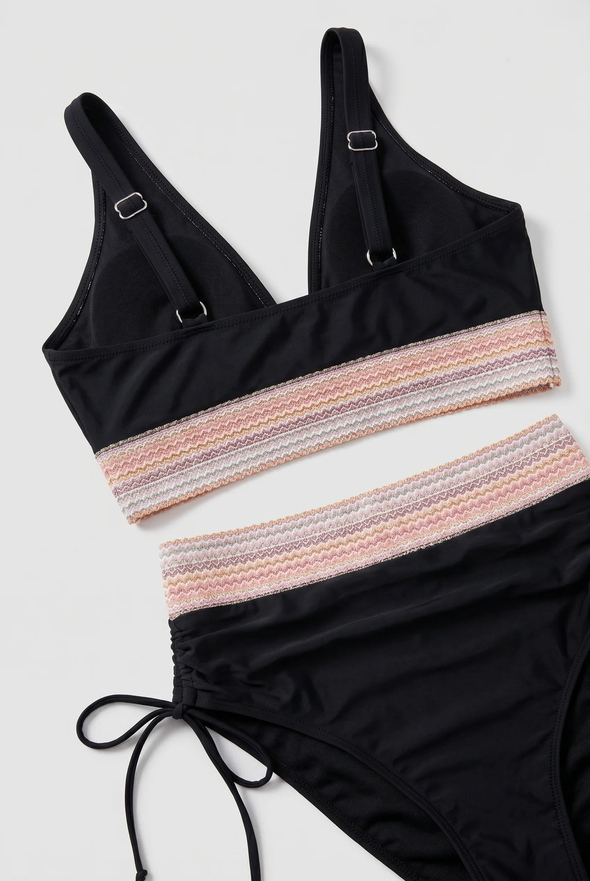 Close-up flat lay of the bikini top and bottom showing the woven zigzag trim and side drawstring ruching