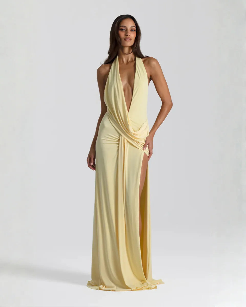 Front view of a model in a pale yellow halter neck maxi dress with deep plunge neckline and draped waist