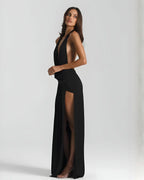 Side view of the black maxi dress showing the open side cutout and high slit with sheer fabric fall