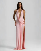 Front view of a model in a soft pink halter neck maxi dress with draped wrap waist and side slit