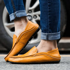 Front angle of both tan leather loafers worn with rolled-up jeans, feet crossed while walking