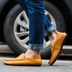 Side profile of tan leather loafers in motion, worn with denim, showing flexible rubber sole