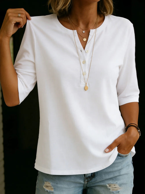 White Henley top shown with model holding the shoulder, revealing the button placket and relaxed fit