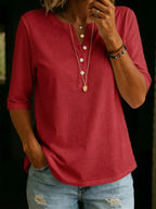 Red Henley-collar top with half sleeves, worn with layered necklaces and ripped denim