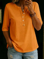 Orange Henley-collar top shown front-on, highlighting the soft cotton texture and buttoned placket