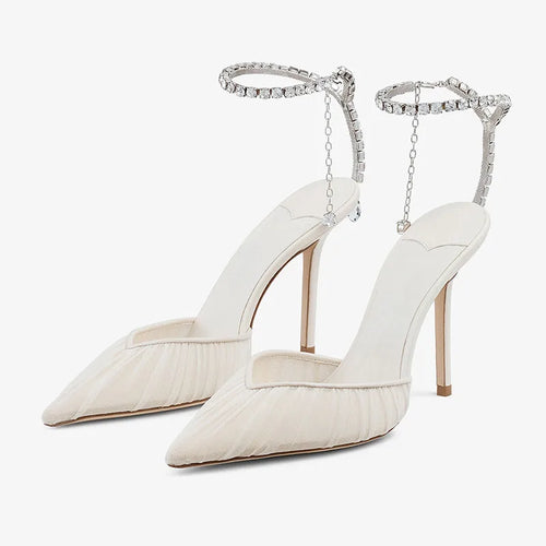 Front angled view of a pair of ivory mesh pointed-toe heels with ruched draping and a crystal ankle strap