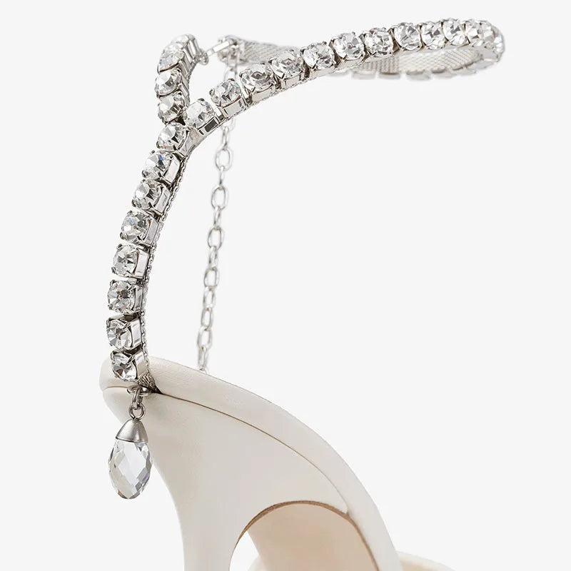 Close-up of the crystal ankle strap and dangling teardrop charm against the ivory mesh upper