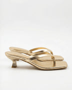 Pair of gold metallic thong sandals with crossover straps and spool-style kitten heel