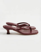 Dark red leather thong sandals with slim crossover straps on a low kitten heel