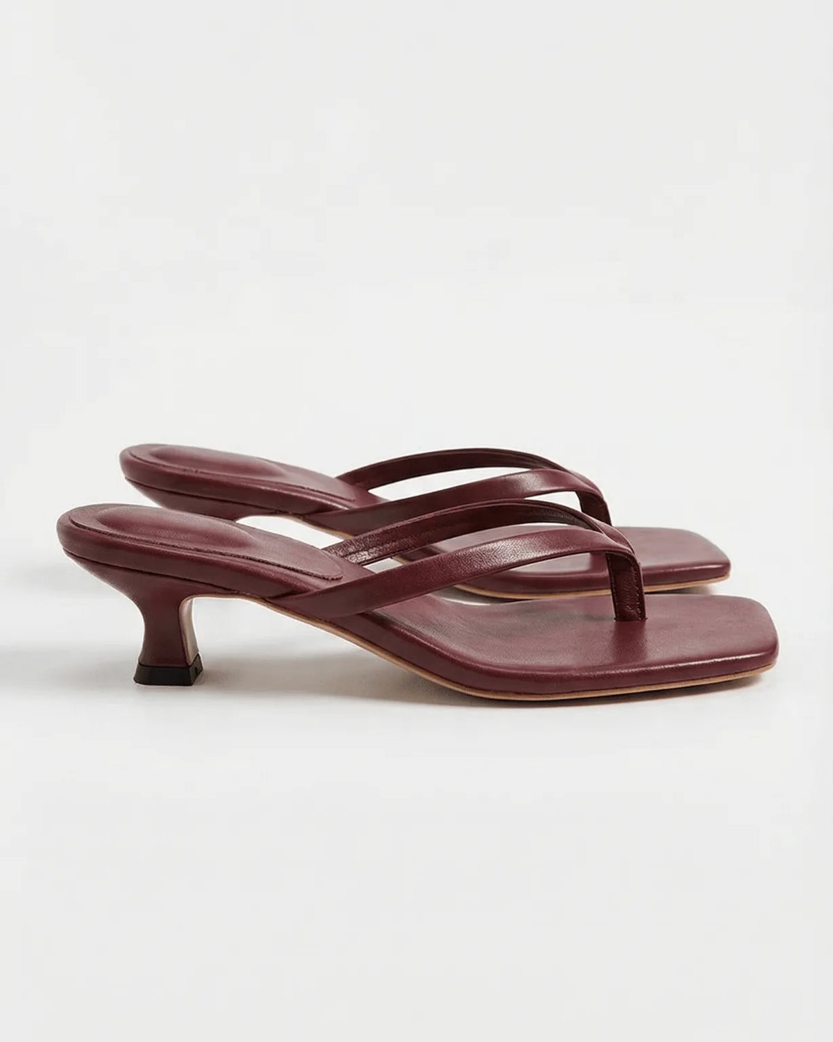 Dark red leather thong sandals with slim crossover straps on a low kitten heel