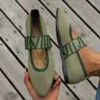 Pair of army green knit pointed-toe flats with tonal striped strap, one held up for detail