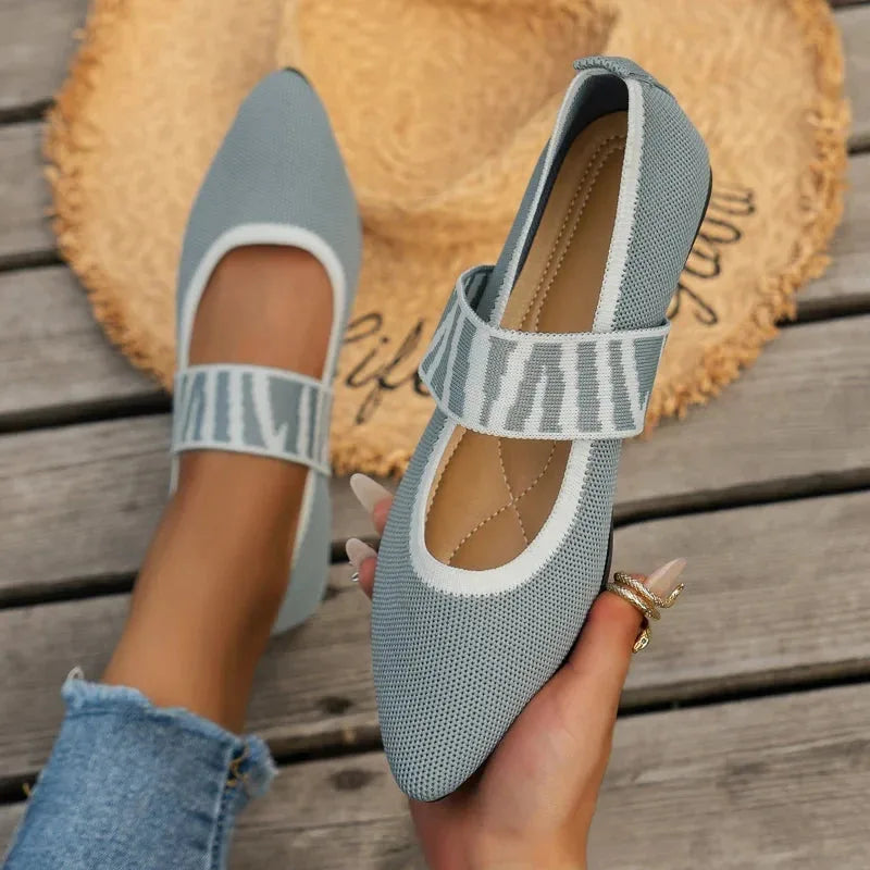 Side profile of beige knit flats showing pointed toe, low sole and brown trim detail on decking