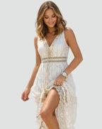 Front view of a sleeveless cream lace maxi dress with plunging V-neckline and tasselled tie waist