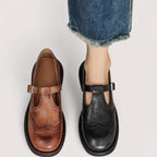 Brown and black Mary Jane pairs placed side by side, one shoe worn on a foot, comparing both colourways
