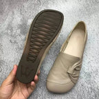 Beige leather flat sole with grip tread, held in hand next to the matching shoe on display