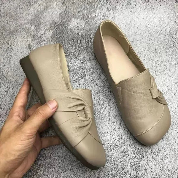 Pair of beige leather flats shown from above with soft rounded toes and knotted upper detail