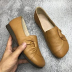 Pair of black leather flats shown together, displaying the smooth embossed leather and wedge sole