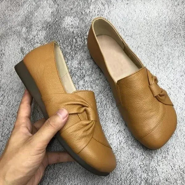 Pair of black leather flats shown together, displaying the smooth embossed leather and wedge sole