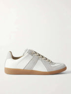Side profile of a white leather sneaker with grey suede panel stripes, cream laces and a gum rubber sole