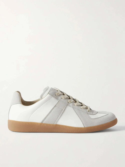 Side profile of a white leather sneaker with grey suede panel stripes, cream laces and a gum rubber sole