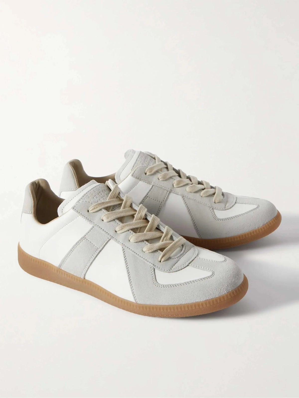 Front angled view of a matching pair of white leather and grey suede lace-up sneakers on a plain background