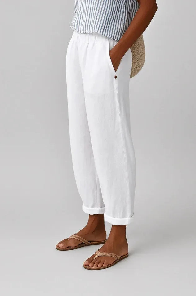 White linen-look cropped trousers with cuffed hem and side pocket, paired with striped top and woven sandals