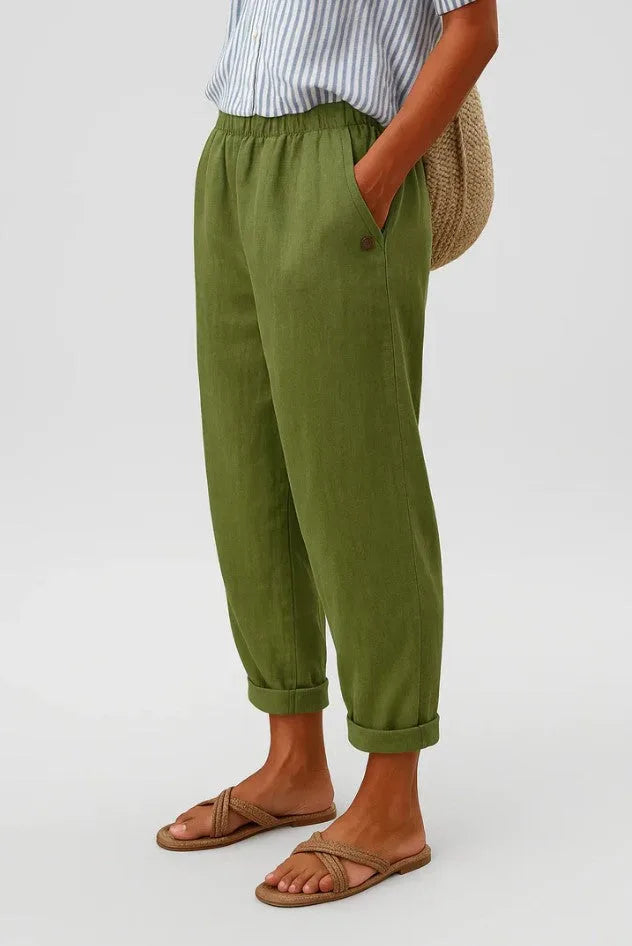 Olive green cropped trousers with rolled cuffs, relaxed tapered leg and hand resting in side pocket