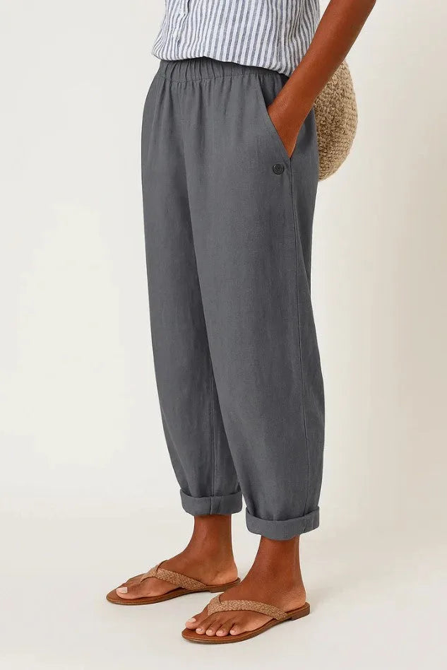 Dark grey cropped trousers with elasticated waist and tonal button pocket, shown with woven thong sandals