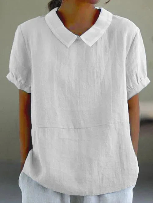 White linen-look blouse with soft folded collar and cuffed short sleeves, shown on model from chest down