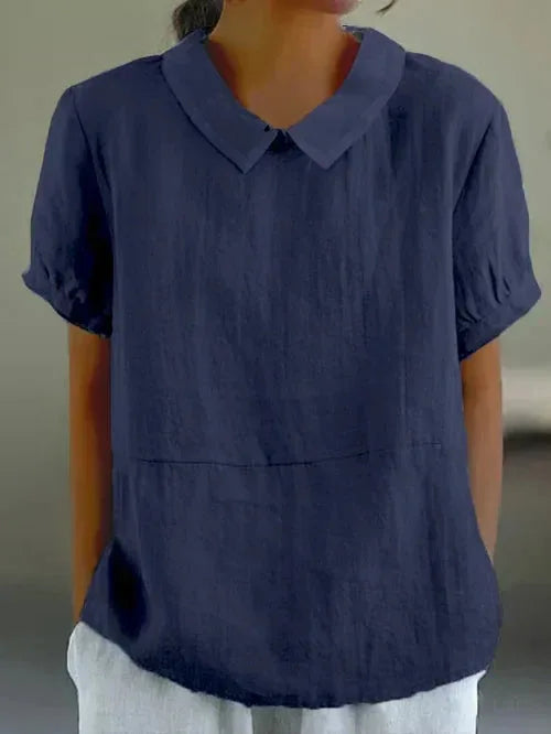 Navy blue linen-look blouse with soft collar and short sleeves, worn with light grey trousers