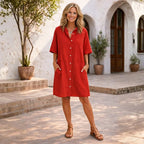Red linen button-up shirt dress with half sleeves and two front patch pockets, worn with tan strappy sandals.